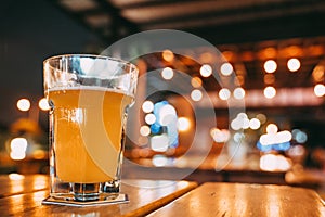 One pint of beer on restaurant table with copy space on blur bokeh background. Happy event celebrations, nightlife at pub concept