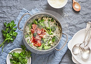 One pot orzo primavera. Orzo pasta with asparagus, broccoli, green peas and cream in a saucepan. On a light background