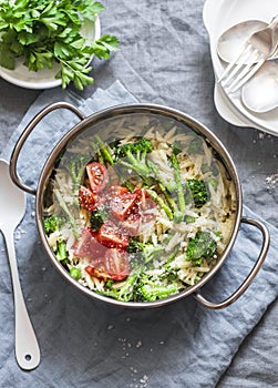 One pot orzo primavera. Orzo pasta with asparagus, broccoli, green peas and cream in a saucepan. On a light background