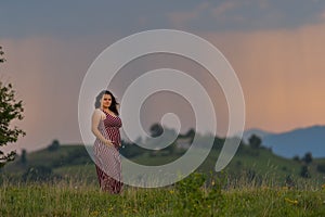 One pregnant woman on sunset landscape