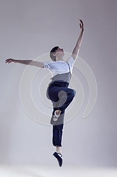 One Professional Caucasian Male Ballet Dancer Performing in Flight With Hands Outspread in Studio Over White