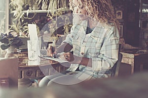 One professional lady working at the desk inside her store shop. Modern smart woman writing at the cafe with a laptop on the table