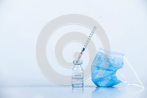 One protective medical mask, a tube with the inscription `Vaccine` and a syringe on a white background. Virus vaccine concept. C