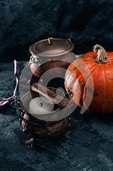 One pumpkin squash and copper or brass witch pots with candles close. uo