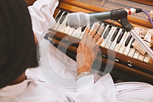 Punjabi Singer with black turban is playing harmonium and singing at Gurudwara photo