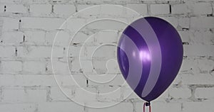 One purple balloon on bricky white wall background