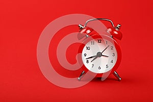 One red alarm clock over red background close up