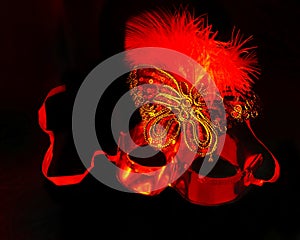 one red carnival Venetian mask isolated on a black background. selective focus.