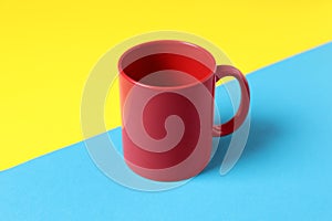 One red ceramic mug on color background