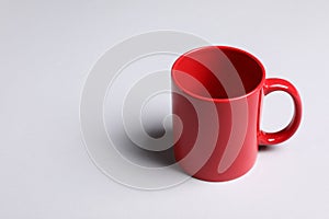 One red ceramic mug on light background, space for text