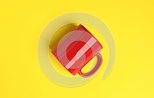 One red ceramic mug on yellow background, top view