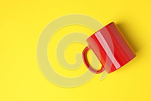 One red ceramic mug on yellow background, top view. Space for text