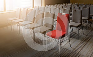 One red chair different from others in empty conference room