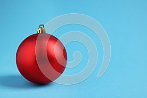 One red Christmas ball on light blue background. Space for text