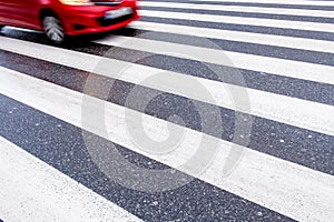 One red, fast, dangerous blurred car on the crosswalk, no people, wet asphalt, empty space