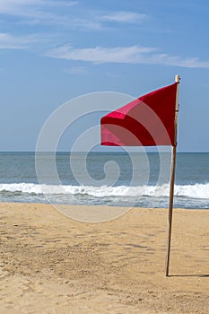One red flag on the beach with a very calm ocean