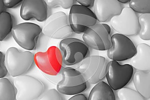 One red heart among a lot black and white hearts on white background top view. Background for Valentine`s day, birthday, holiday,