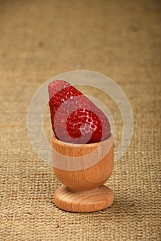 One red mellow strawberry in eggcup on canvas