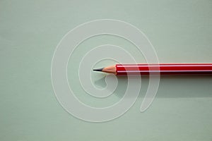 One red pencil on a light green background.