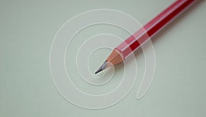 One red pencil on a light green background.