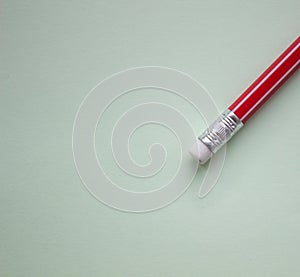 One red pencil on a light green background.