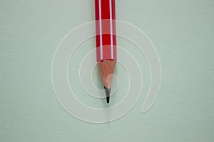 One red pencil on a light green background.