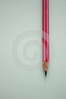 One red pencil on a light green background.