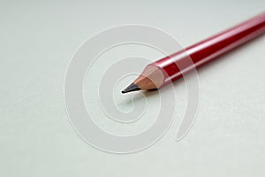 One red pencil on a light green background.