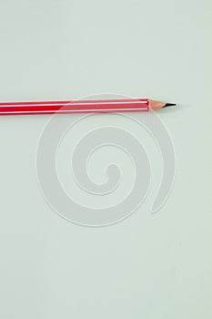 One red pencil on a light green background.