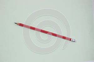 One red pencil on a light green background.