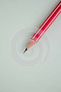 One red pencil on a light green background.