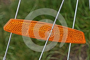 One red plastic reflector on the gray metal spokes of a bicycle wheel