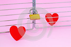 One red silk heart is in a cage locked with padlock and another one is outside. To meet a heartmate and to open heart for soulmate