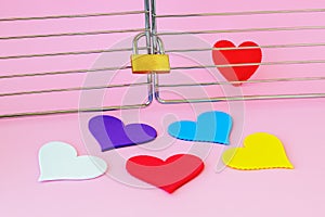 One red silk heart is in a cage locked with padlock. Five multicolored hearts are outside. To find the true love among people and