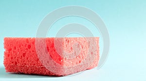One red sponge on a blue background is used to wash and erase the dirt used by housewives in everyday life. They are made of