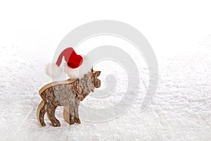 One reindeer with red santa hat on snowy white wooden background