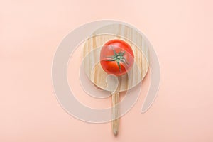 One Ripe Organic Tomato with Green Leaves on Round Wood Cutting Board on Pink Background. Food Poster Banner Streamer