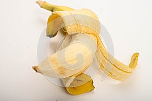 One ripe yellow partially peeled banana on a white background. Close up