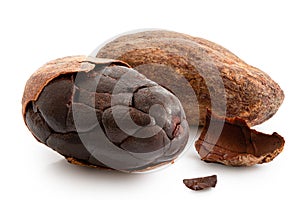 One roasted partly peeled and one unpeeled cocoa bean isolated on white photo