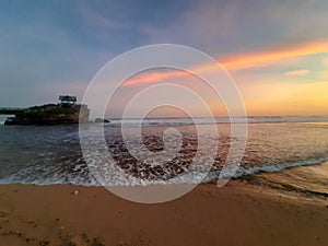 One rock creeping out of the ocean on transparent water at Kukup beach