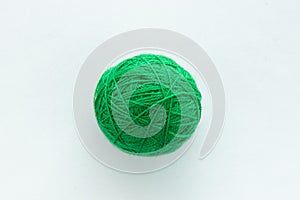 One round ball of green color in the center of the frame on a white woven background on the theme of hand-made hobby knitting