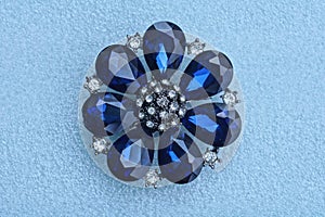 one round silver jewelry brooch in the shape of a flower with blue stones