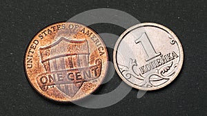 One Russian kopeck and an American cent on a dark background