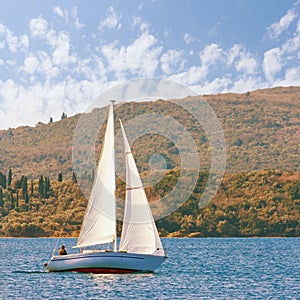 One sailboat with white sail on the water. Montenegro, Bay of Kotor. Travel concept