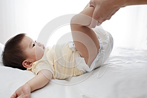 A small cute little baby girl was lying down, her diaper was being changed by her dad photo