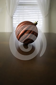 One Red Christmas Ball on Table in front of window