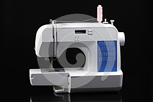 One sewing machine with spool of thread on black background