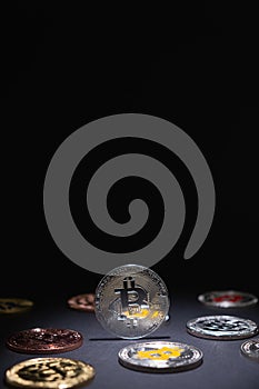 One Shiny Silver Bitcoin close up, centered with other bitcoins coins lied on the desk on a dark background