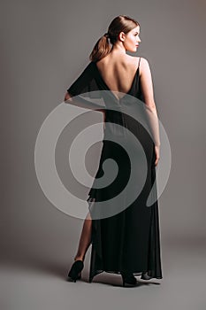 One shoulder ruffled maxi dress in black. Asymmetric open-back chiffon gown with a strap, split and frills