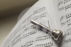 One Silver Trumpet mouthpiece on sheet music book